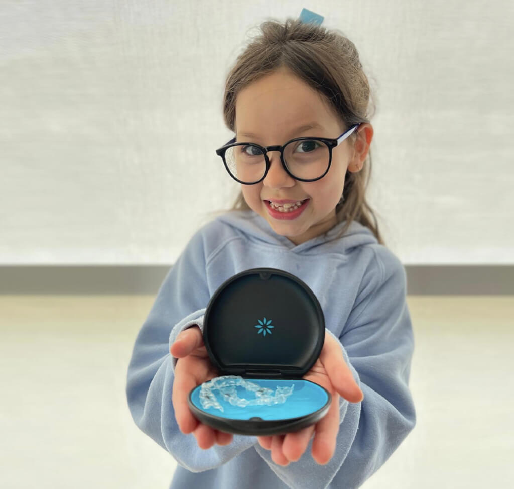Young Seapoint patient holding her clear aligners case